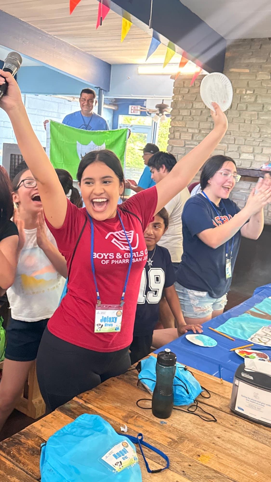 A teen volunteer cheering with arms raised at a Boys & Girls Club of Pharr–San Juan camp